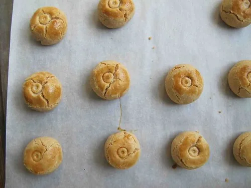 Kue kacang bulat yang baru matang berjajar di atas kertas roti di loyang