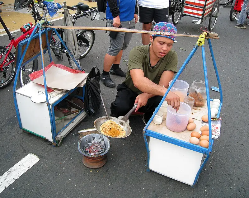 Pedagang kerak telor memasak di wajan kecil di atas anglo arang saat hari bebas kendaraan di Jakarta