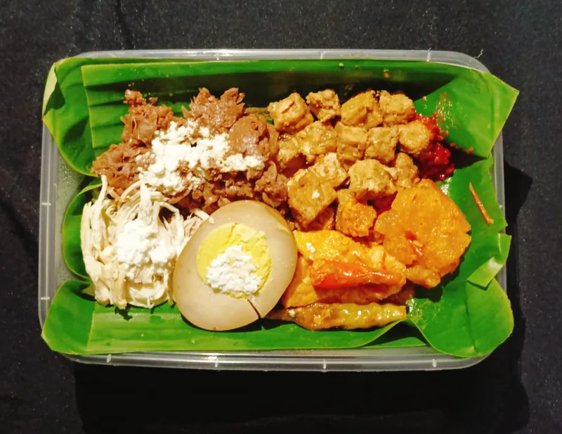 Gudeg nangka muda dengan ayam suwir, telur pindang, sambal krecek, dan tempe di atas daun pisang