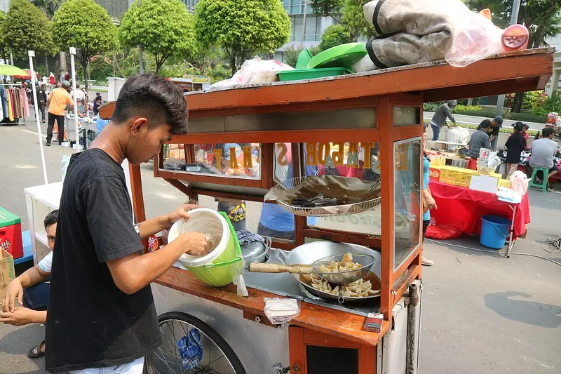 Pedagang batagor menyiapkan pesanan di gerobak kaki lima di pinggir jalan Jakarta
