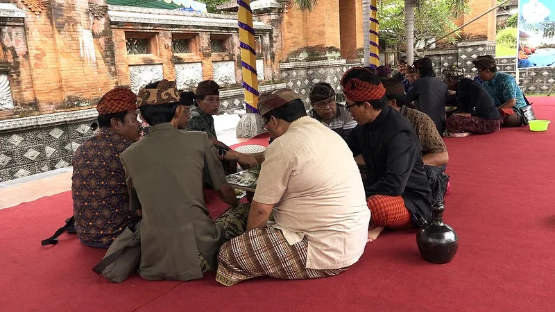 Kelompok pria berpakaian adat Bali duduk melingkar makan bersama dalam tradisi megibung di Karangasem