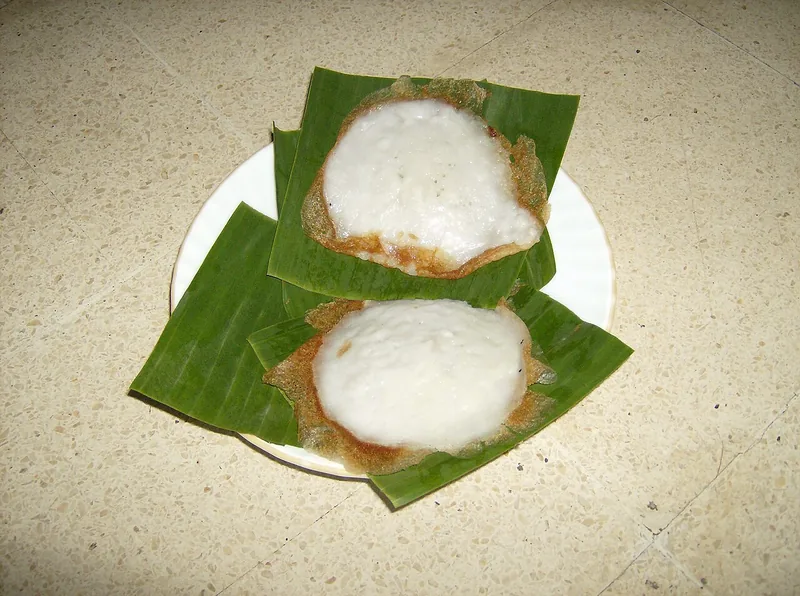 Dua serabi Solo putih bertepi kecokelatan renyah di atas alas daun pisang