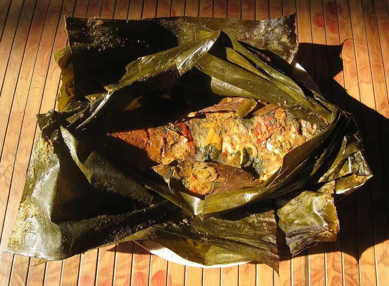 Pepes ikan mas khas Sunda dalam bungkus daun pisang yang sudah dibuka, berbumbu kuning
