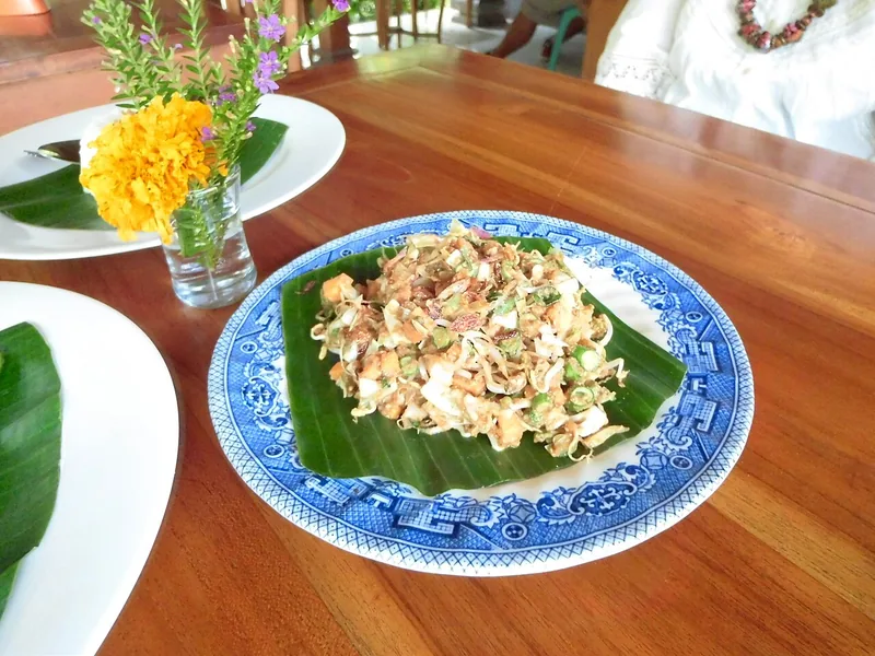 Karedok berisi sayuran mentah dan kacang panjang berbumbu kacang di atas daun pisang