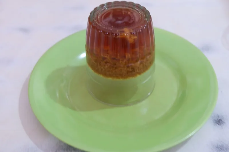 Agar-agar dua lapis cokelat gula merah dan putih santan dari cetakan gelas di piring hijau