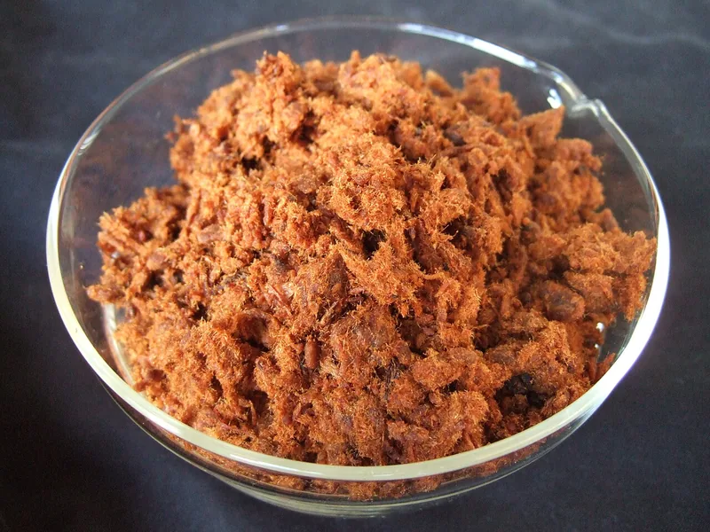 Abon sapi berserat halus berwarna cokelat kemerahan dalam wadah kaca