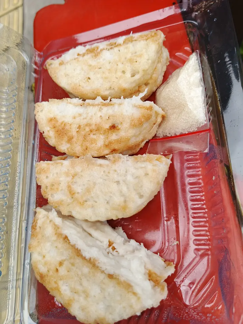 Potongan kue pancong memperlihatkan bagian dalam putih lembut di atas nampan merah