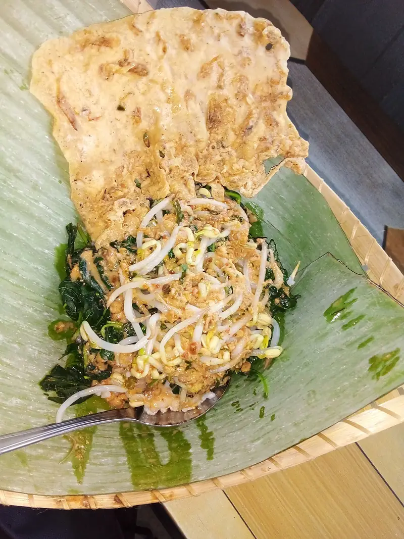 Pecel sayur bayam dan tauge bersiram sambal kacang dengan rempeyek lebar di atas daun pisang