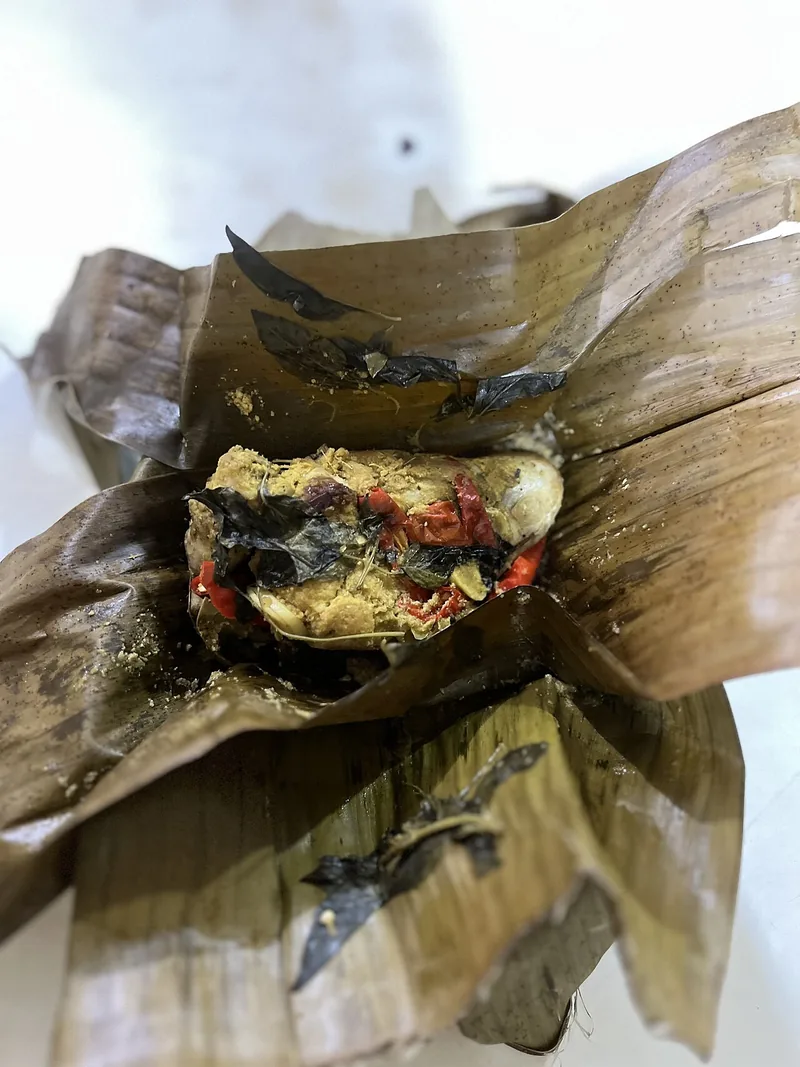 Pepes tahu yang dibuka dengan isian tahu, cabai merah, dan daun kemangi di atas daun pisang