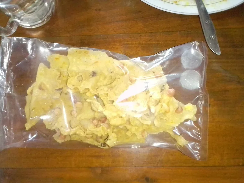 Peyek kacang disimpan dalam kantong plastik bening tertutup di atas meja kayu