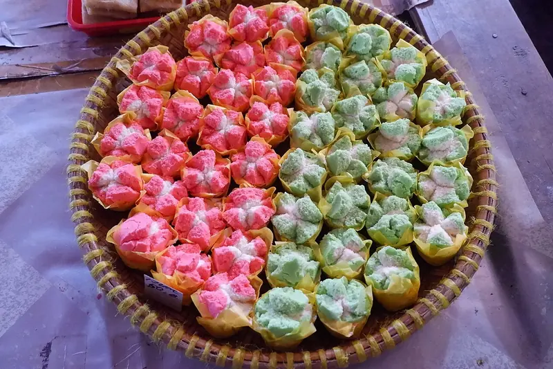 Tampah berisi bolu kukus merah muda dan hijau yang merekah sempurna di bagian atas