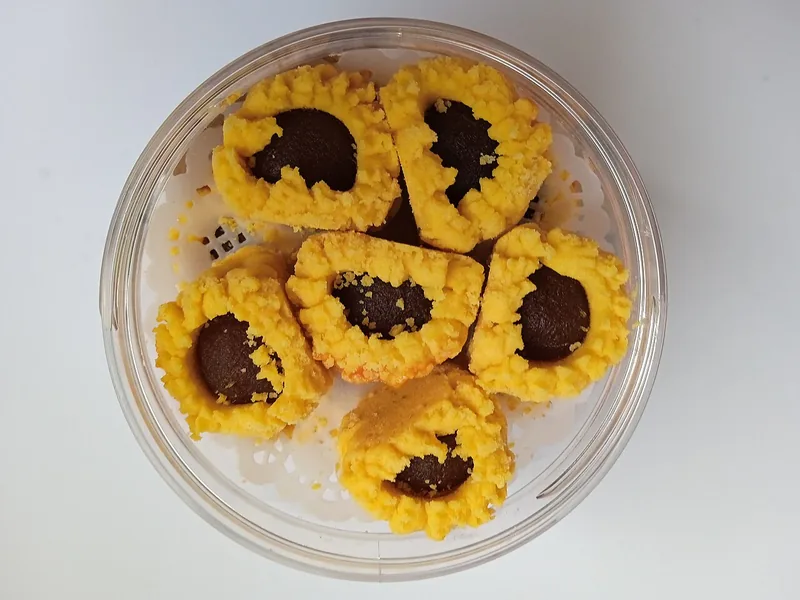 Kue tart nanas dengan isian selai gelap tersusun di dalam toples plastik bening