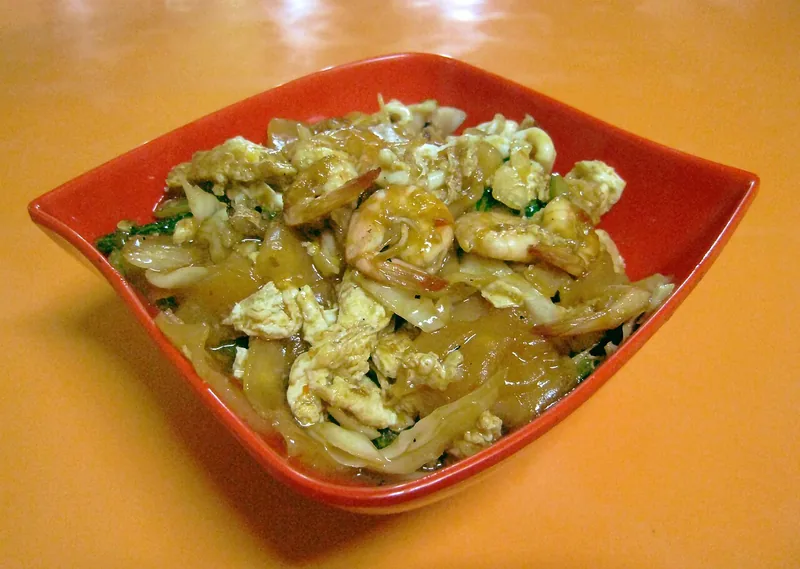 Seblak seafood berisi udang, orak-arik telur, kerupuk basah, dan kol di mangkuk merah