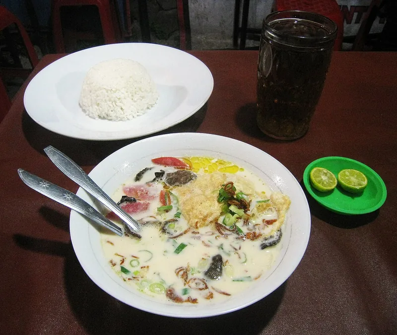 Penyajian soto betawi dengan nasi putih, jeruk limau, dan segelas teh di warung
