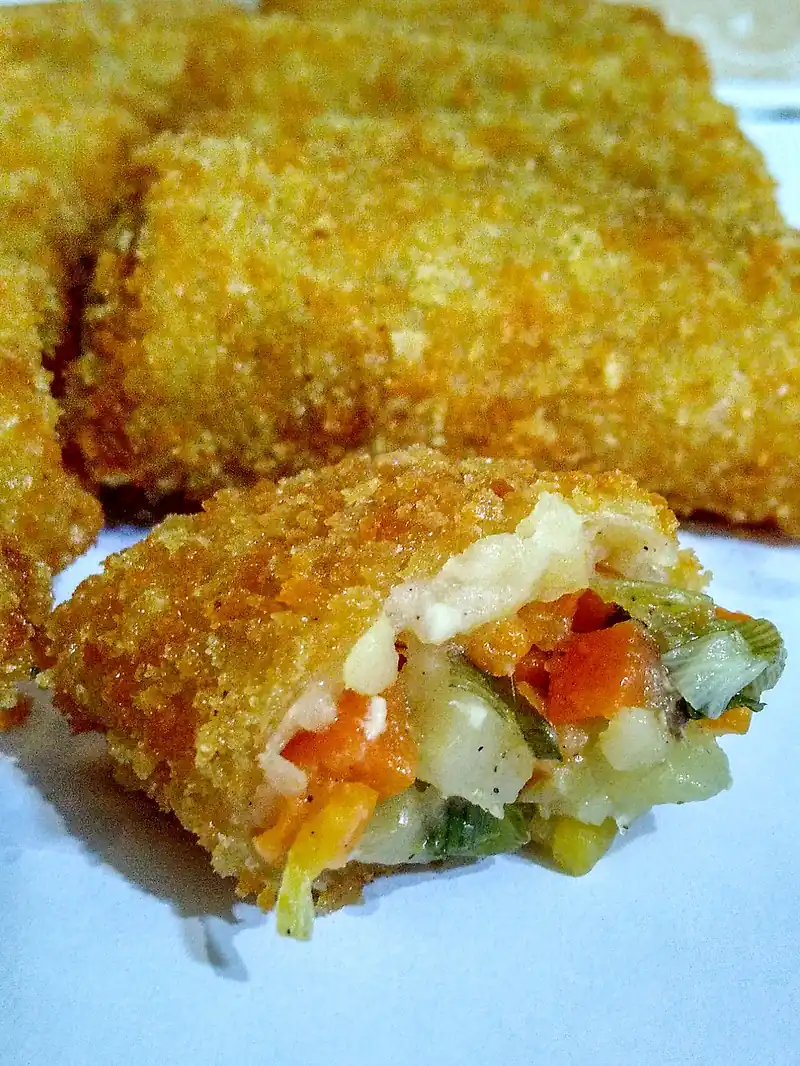 Risol goreng dipotong memperlihatkan isian wortel, kentang, daun bawang, dan mayones yang lembut