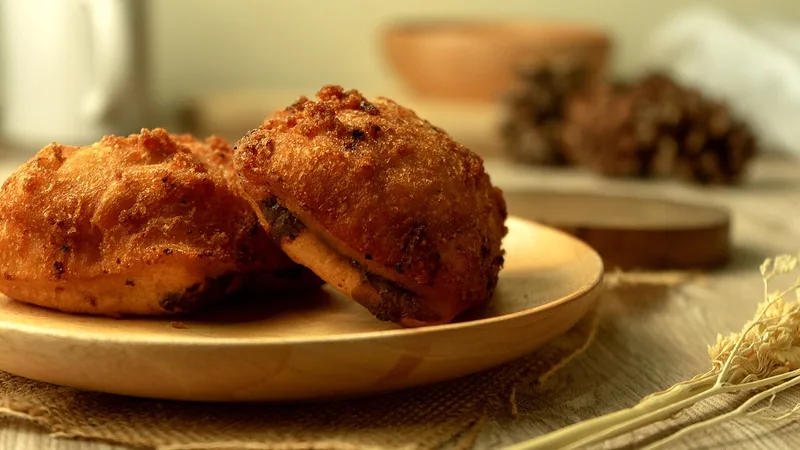 Dua bolang-baling goreng isi cokelat di atas piring kayu