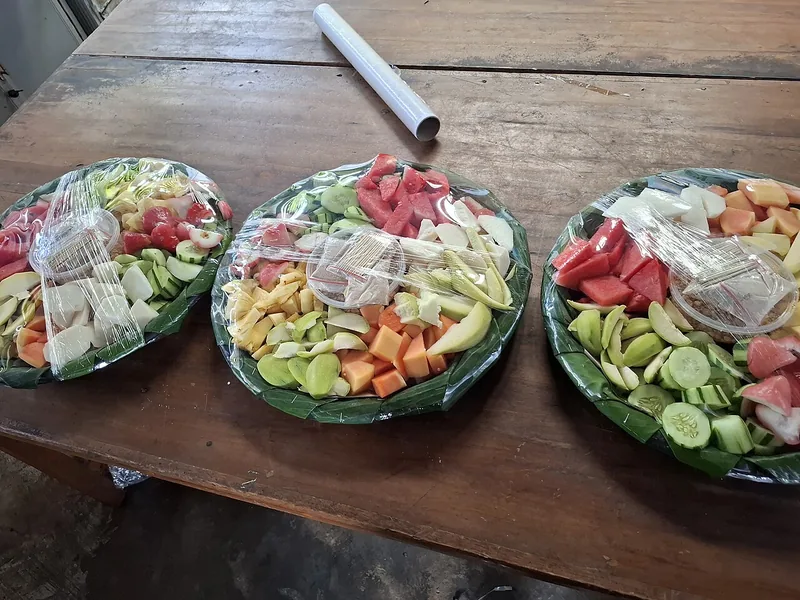 Tiga nampan berisi potongan buah segar untuk rujak seperti semangka, mentimun, pepaya, dan bengkuang