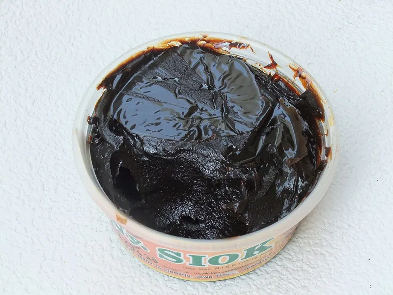 Petis udang hitam pekat dan kental di dalam wadah plastik