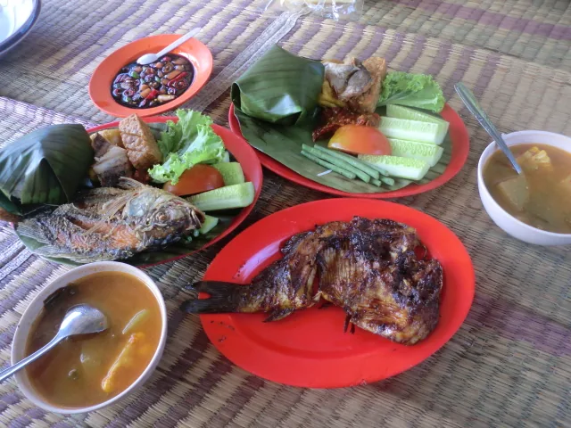 Nasi timbel berbungkus daun pisang dengan ikan bakar, ikan goreng, lalapan, sambal, dan sayur asem