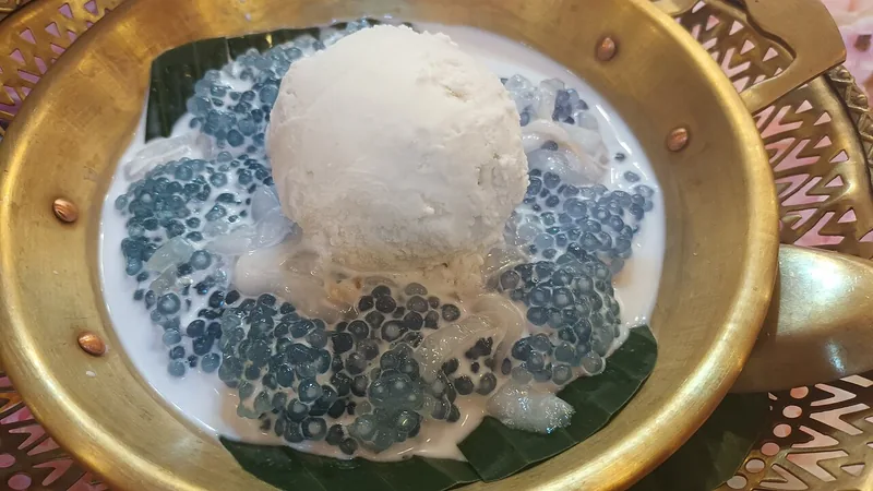 Sagu mutiara kebiruan dalam kuah putih dengan es krim di wadah berwarna keemasan
