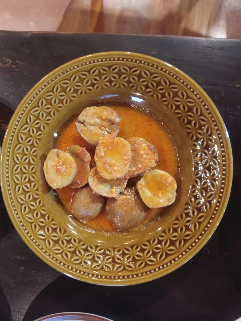 Semangkuk jengkol berkuah bumbu merah oranye