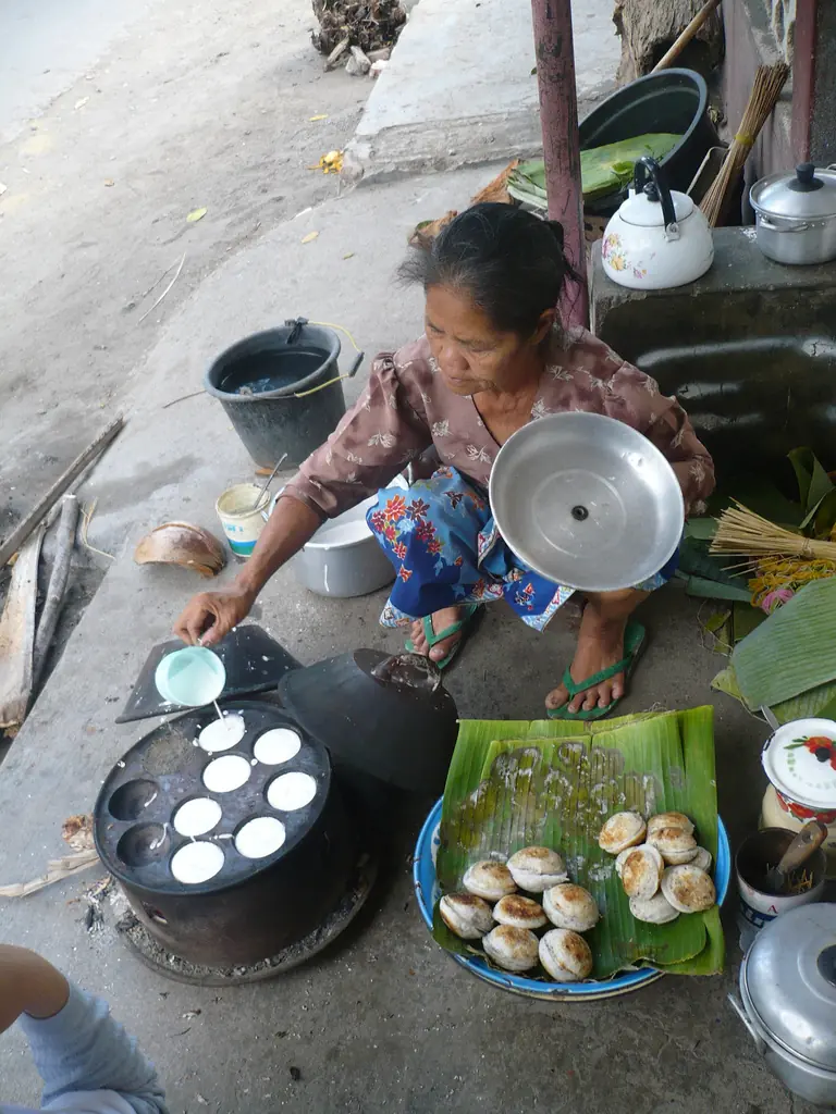 Penjual serabi Lombok membuka tutup cetakan untuk mengecek kematangan serabi