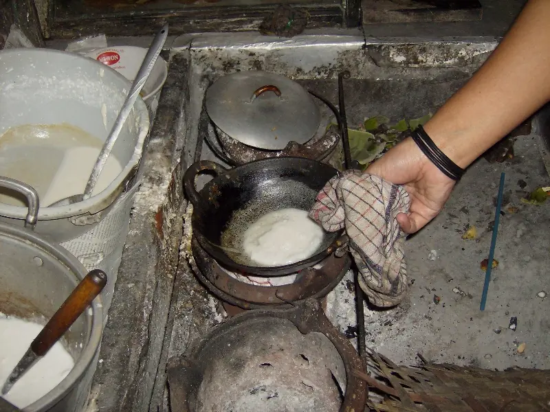 Adonan serabi dimasak dalam wajan kecil di atas tungku arang oleh pedagang serabi Solo