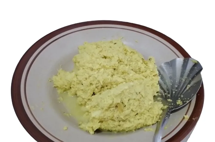 Kelapa parut yang sudah dicampur bumbu kuning halus di atas piring sebelum disangrai