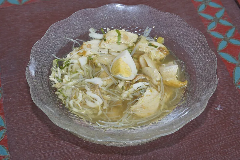 Soto Madura dalam mangkuk kaca berisi potongan daging, telur rebus, tauge, dan irisan kol berkuah bening