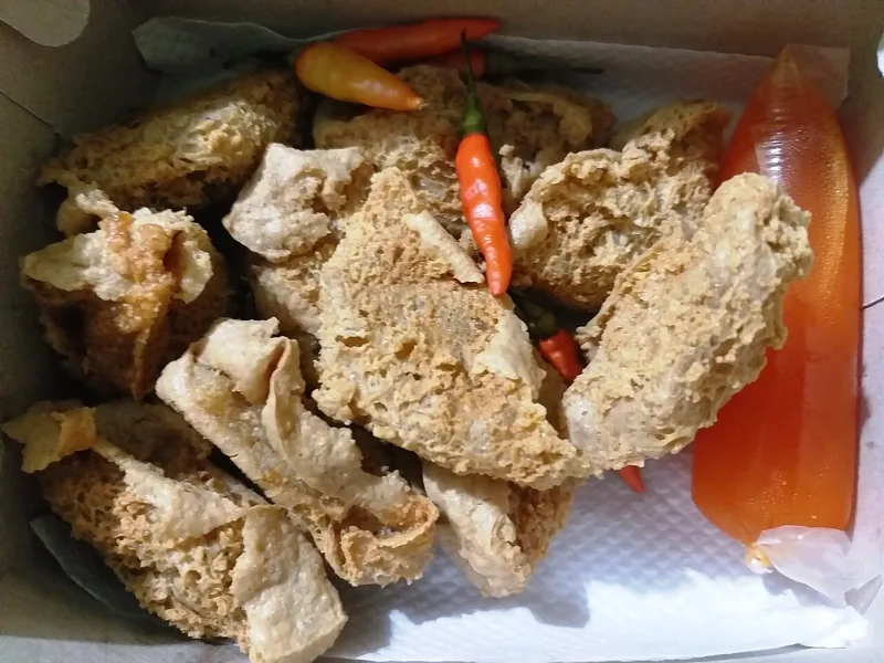 Tahu walik khas Banyuwangi dalam kotak kertas dengan cabai rawit dan saus dalam plastik