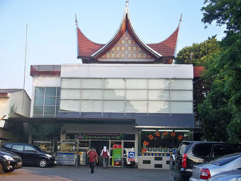 Bangunan rumah makan Padang Sederhana beratap gonjong khas Minangkabau dengan mobil parkir di depan