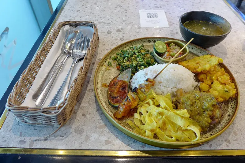 Sepiring nasi campur Bali dengan sate lilit, telur dadar iris, urap kacang panjang, dan sambal matah