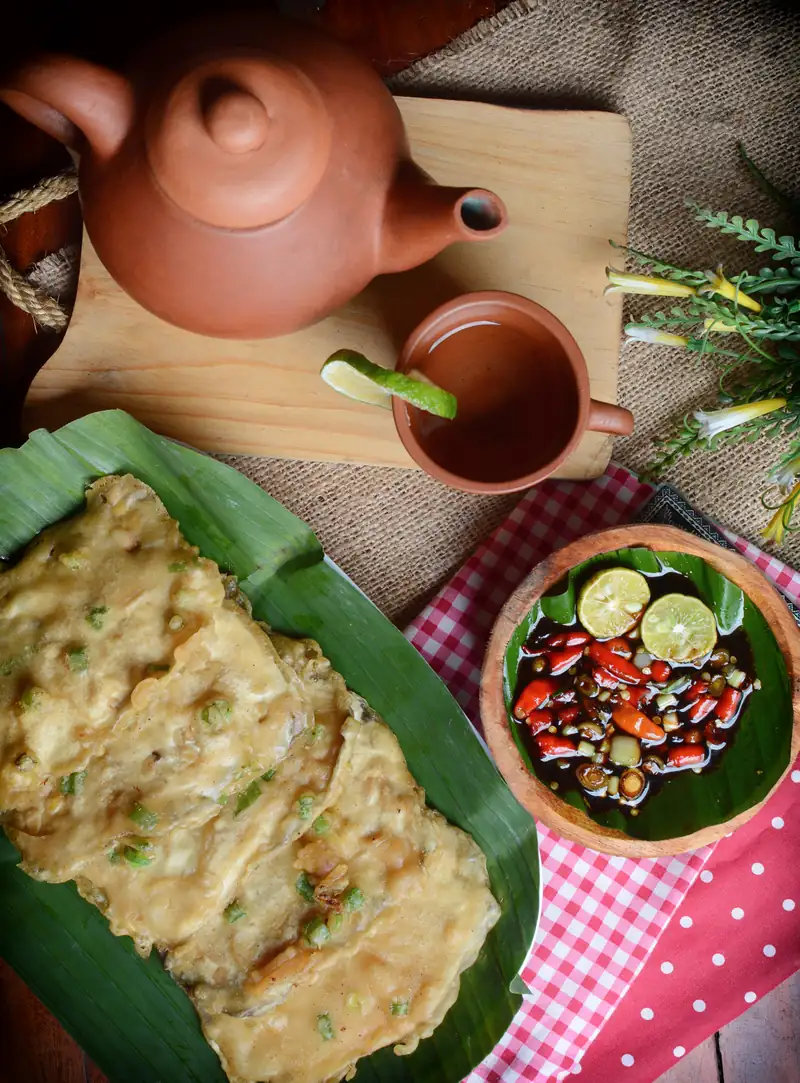 Tempe mendoan di atas daun pisang dengan sambal kecap cabai rawit dan teh dari teko tanah liat
